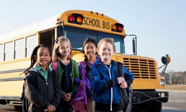 Young children in front of a yellow school bus